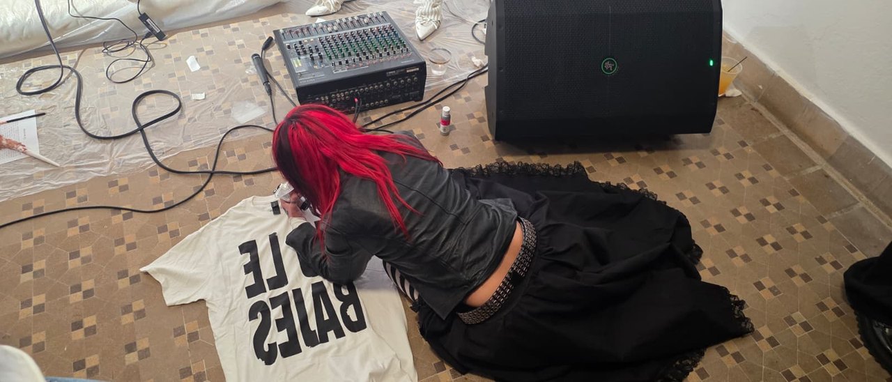 Melodie painting a fan's shirt on the floor.